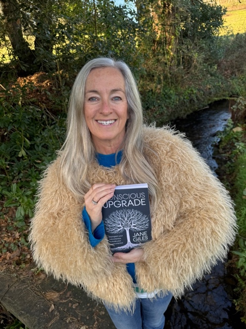 Jane Giles holding her book Conscious Upgrade